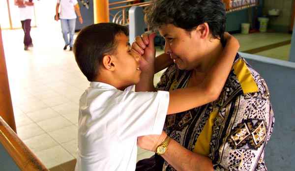 Foto de una maestra con un estudiante cara a cara.