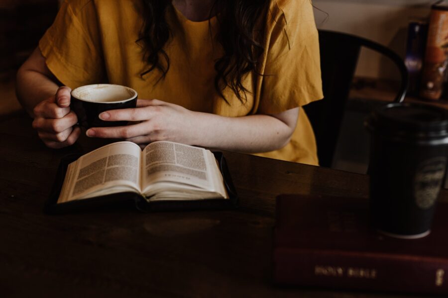 Una mujer leyendo un libro y tomando un cafe