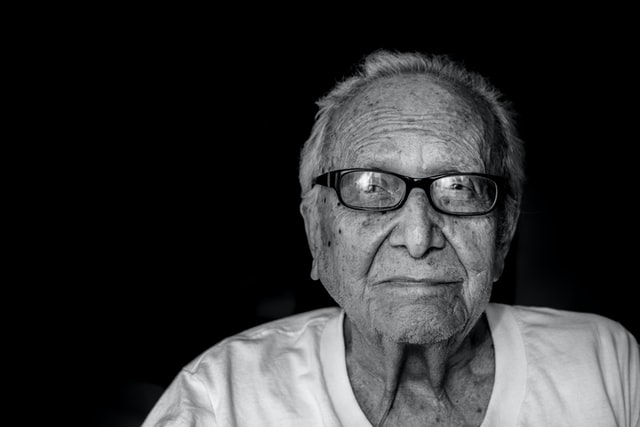 Un adulto mayor con anteojos, mirando a la camara
