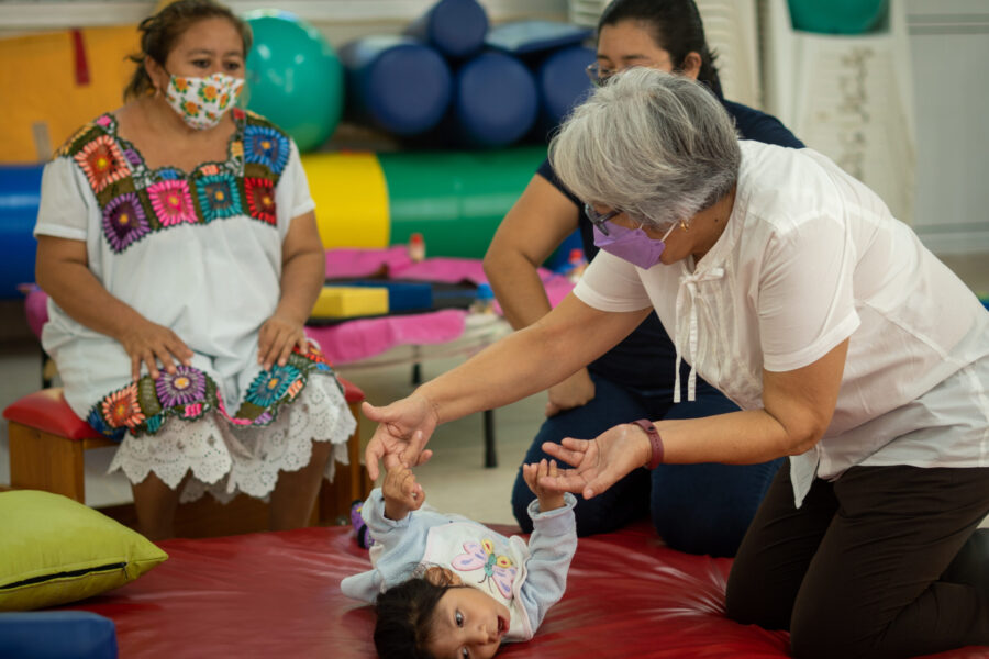 Mama, maestra y consultora de Perkins trabajan con nina con discapacidad.