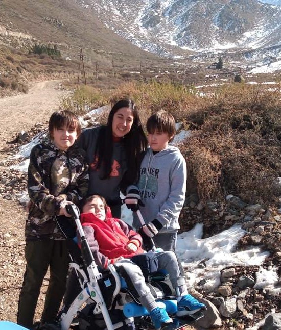 Foto de Flavia con sus tres hijos, Fabricio, Luciano, y Valentino. Los cuatro están en una montaña.