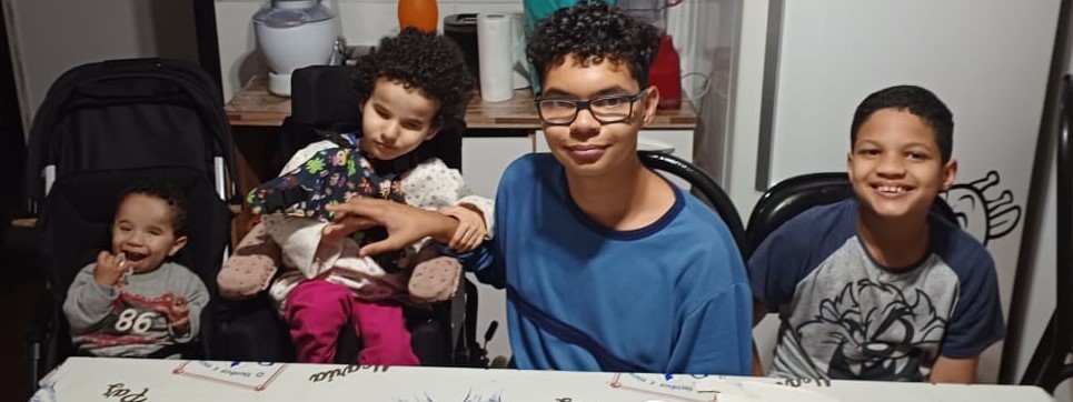 Da esquerda para direita, Lucas, Micaella, Breno e Arhur sentados na mesa da cosinha e sorrindo para a camera.