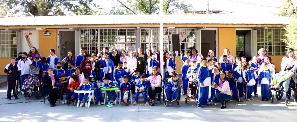 Estudiantes y maestras del Centro de Atención Múltiple VII reunidos fuera del colegio en una tarde soleada