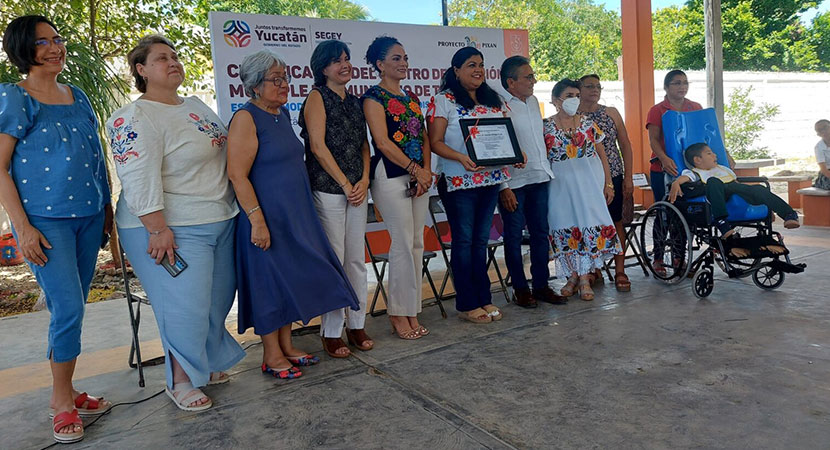 La directora del CAM Tecoh, Sheila López muestra el Certificado de Reconocimiento, a sus lados se encuentran representantes de familias, un estudiante del CAM, la supervisora de la escuela, así como autoridades de la Dirección de Educación Especial, la  Representante,  coordinadora académica, coordinadora familiar de Perkins.