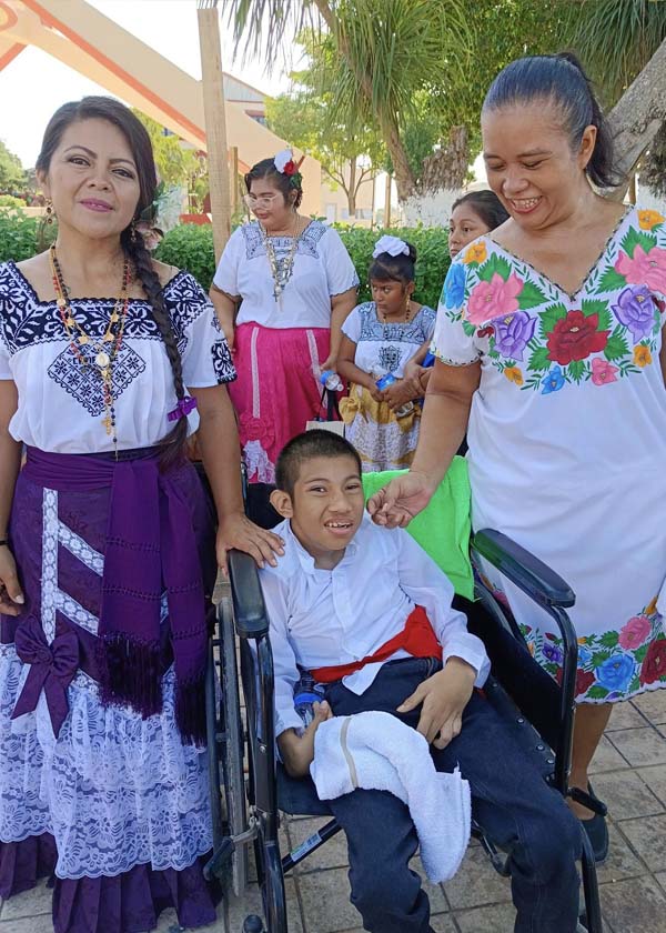 Foto de Adonis en su silla de ruedas con dos de sus maestras.