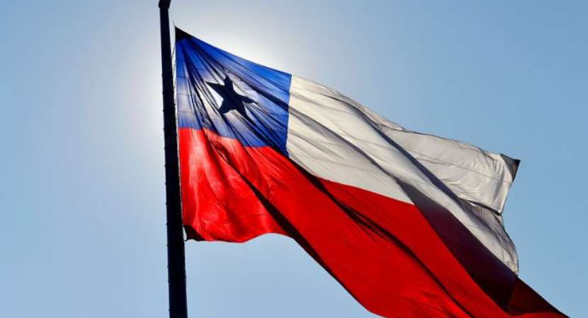 Tras un cielo azul, se ve la bandera de Chile en azul, rojo y blanco, junto con una estrella negra