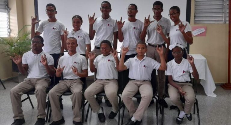 "Once estudiantes jóvenes en su uniforme escolar posan para la cámara haciendo el signo de lenguaje de señas que significa 'amor'