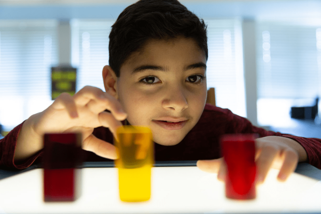 Un niño joven con CVI observa formas tridimensionales coloridas en una caja de luz.