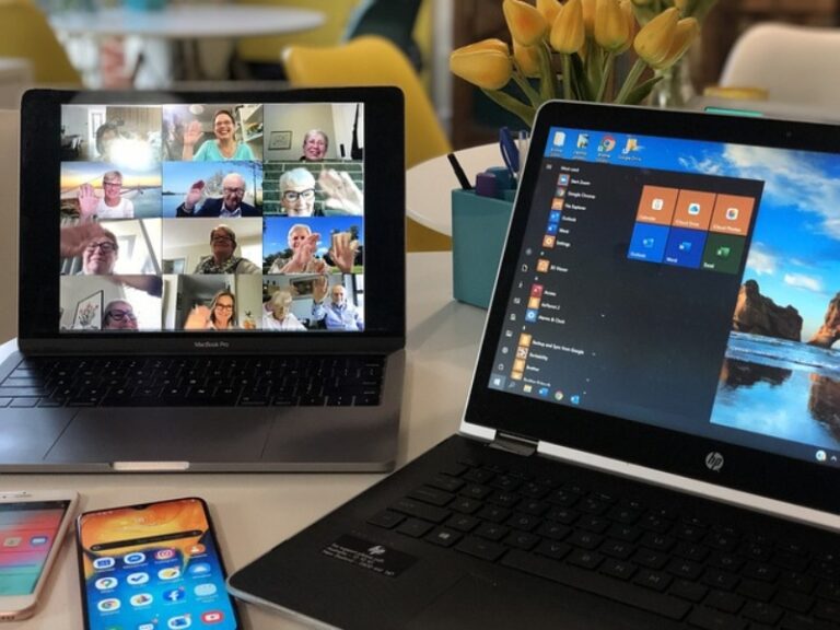 Foto de dos computadoras abiertas con reuniones en las pantallas.