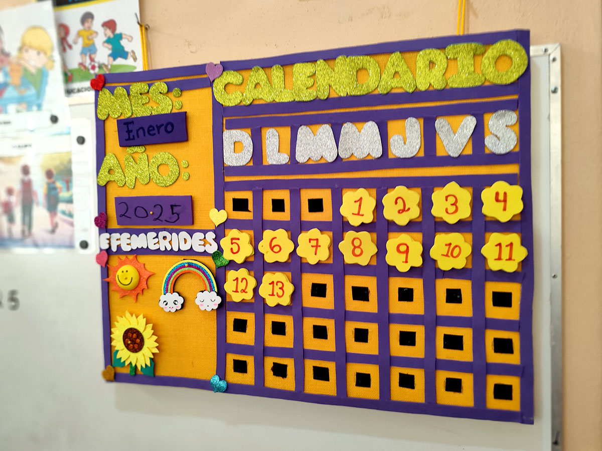 Calendario escolar colorido para enero de 2025, con días de la semana, días numerados y elementos decorativos como un arcoíris y un girasol. El calendario utiliza una variedad de materiales y es muy táctil.