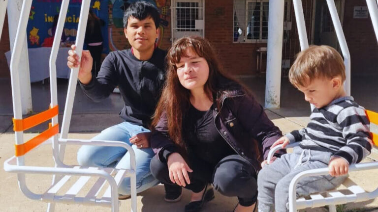 Manu, Emilce, y Naún se sientan juntos al aire libre. Los tres llevan ropa informal y parecen relajados.