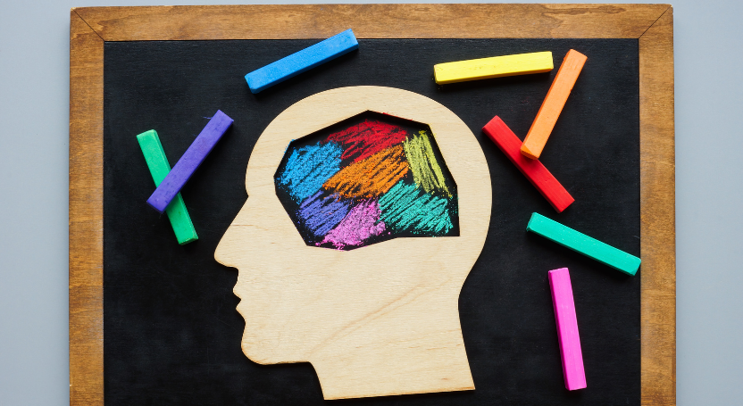 Imagem de um quadro negro com giz e lápis de cor em forma de cabeça humana