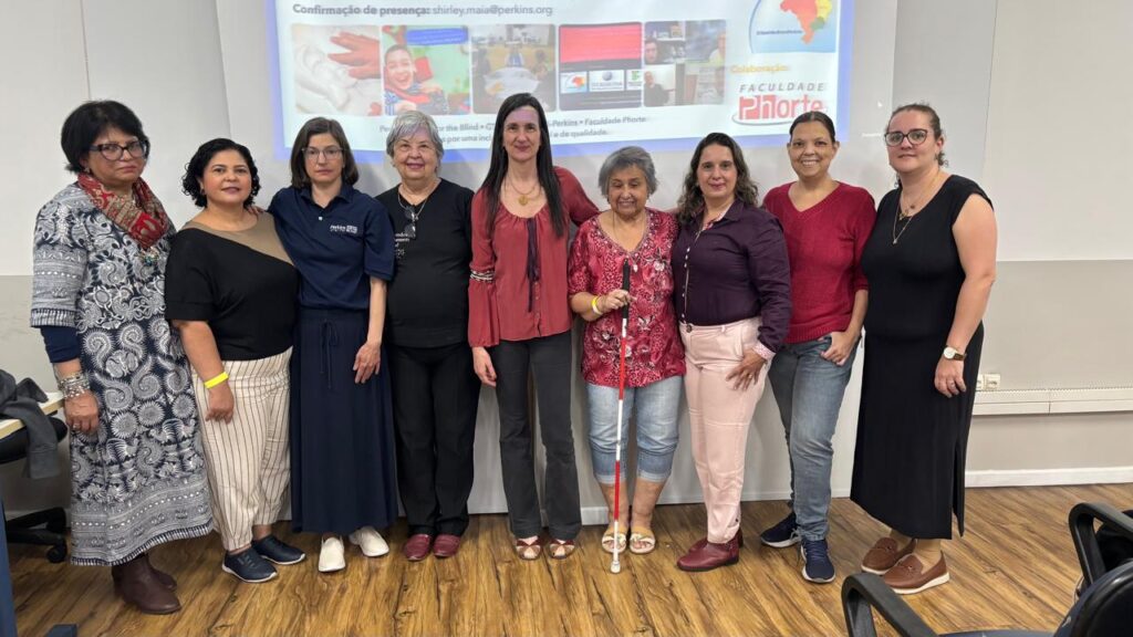 Nove membros do Grupo de Trabalho Estratégico estão juntos em frente a uma tela que projeta uma apresentação.